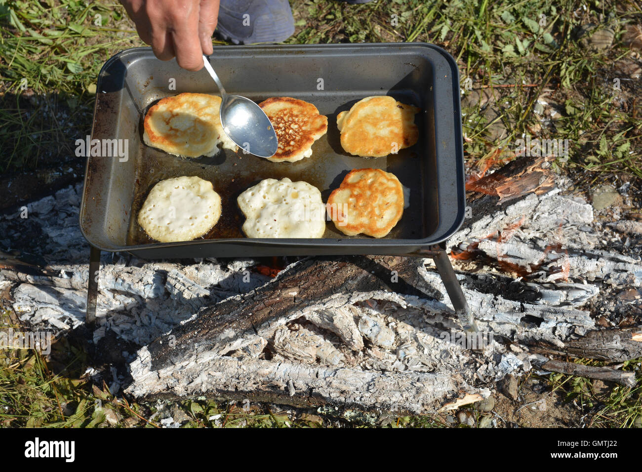 Frühstück auf dem Feuer kochen. Leckere Pfannkuchen auf die Backen Blatt warten auf Reisende. Stockfoto