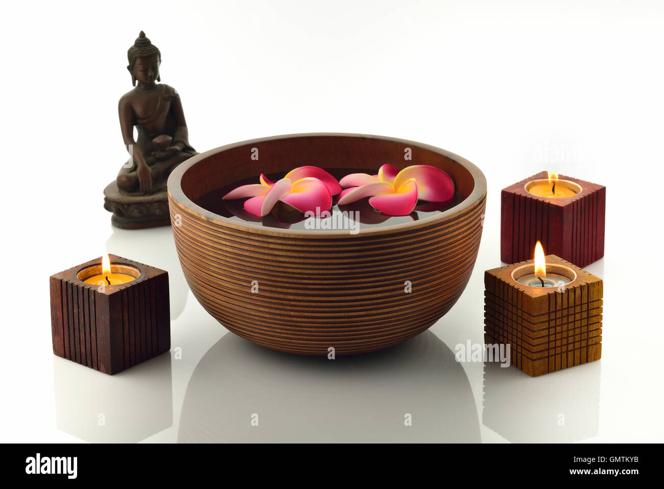 Hölzerne Spa Schüssel mit Buddha-Statue, Kerzen und Blumen schweben Stockfoto