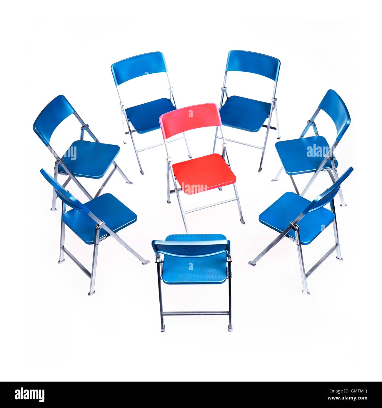 Hot-Seat. Ein Kreis aus blauen Stühlen umgeben von einem roten Stuhl. Stockfoto