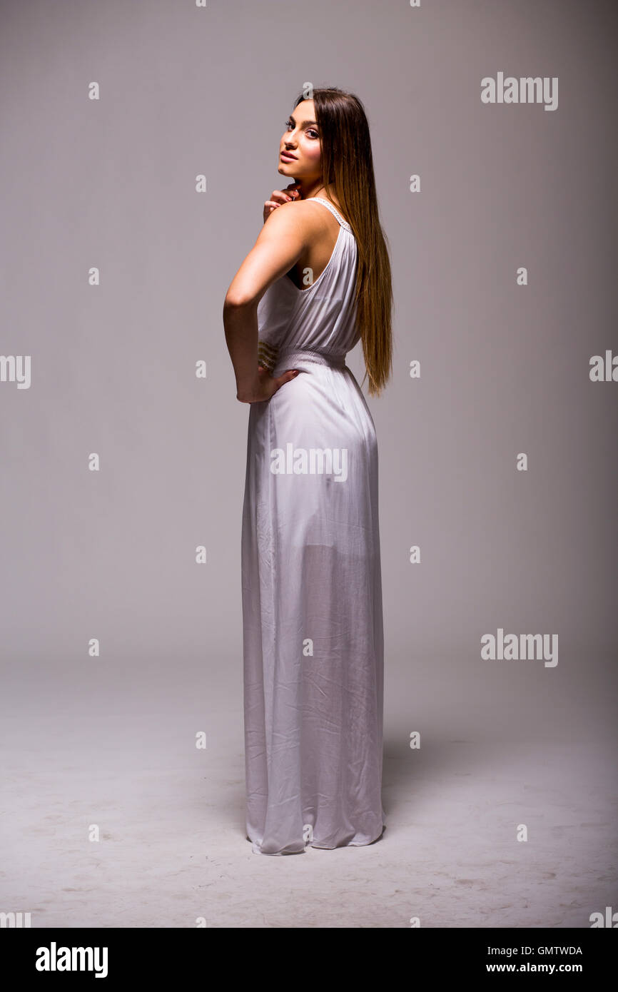 Hübsche junge Frau mit langen Haaren im weißen Kleid im studio Stockfoto