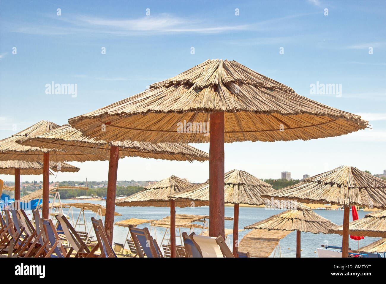 Reihen von Reed Sonnenschirm und Liegestuhl am Strand Stockfoto