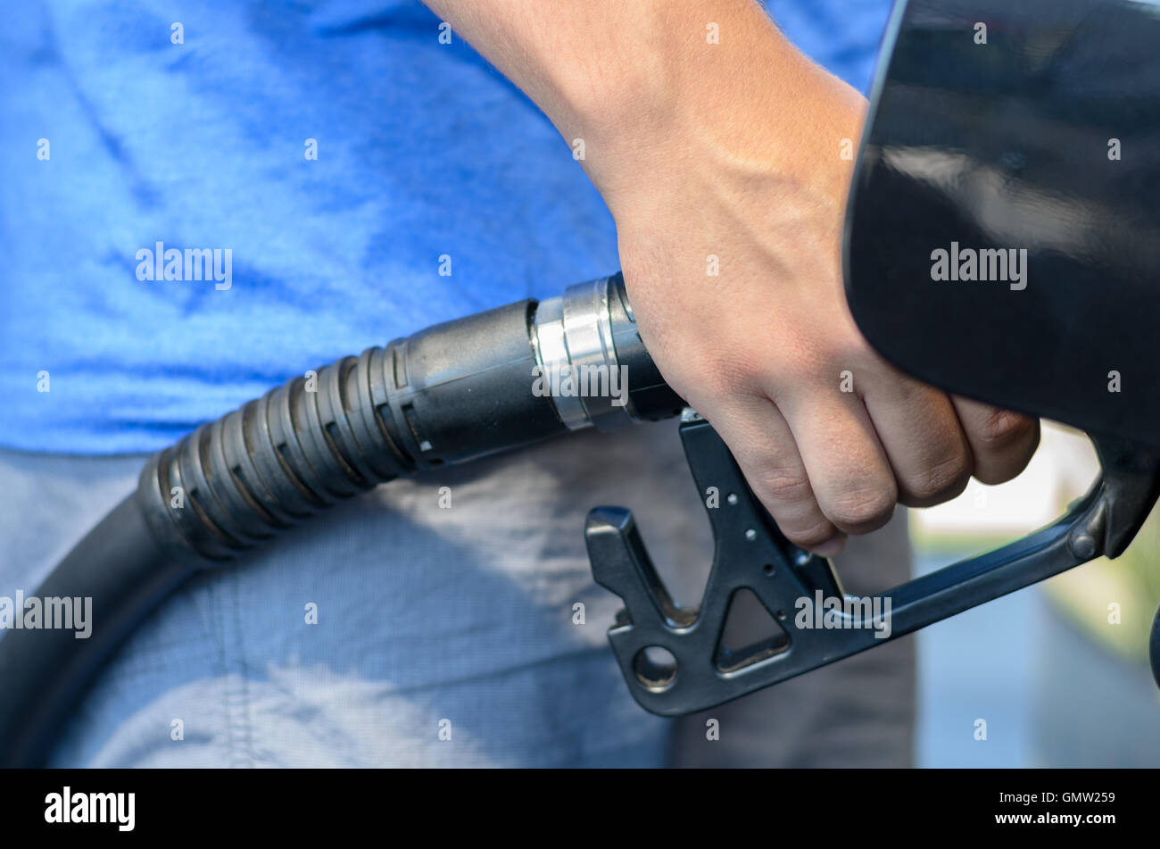 Mann sein Auto mit Benzin in einer Garage zu füllen oder Tankstelle, Nahaufnahme auf seine Hand und die Düse wie er die f verzichtet Stockfoto