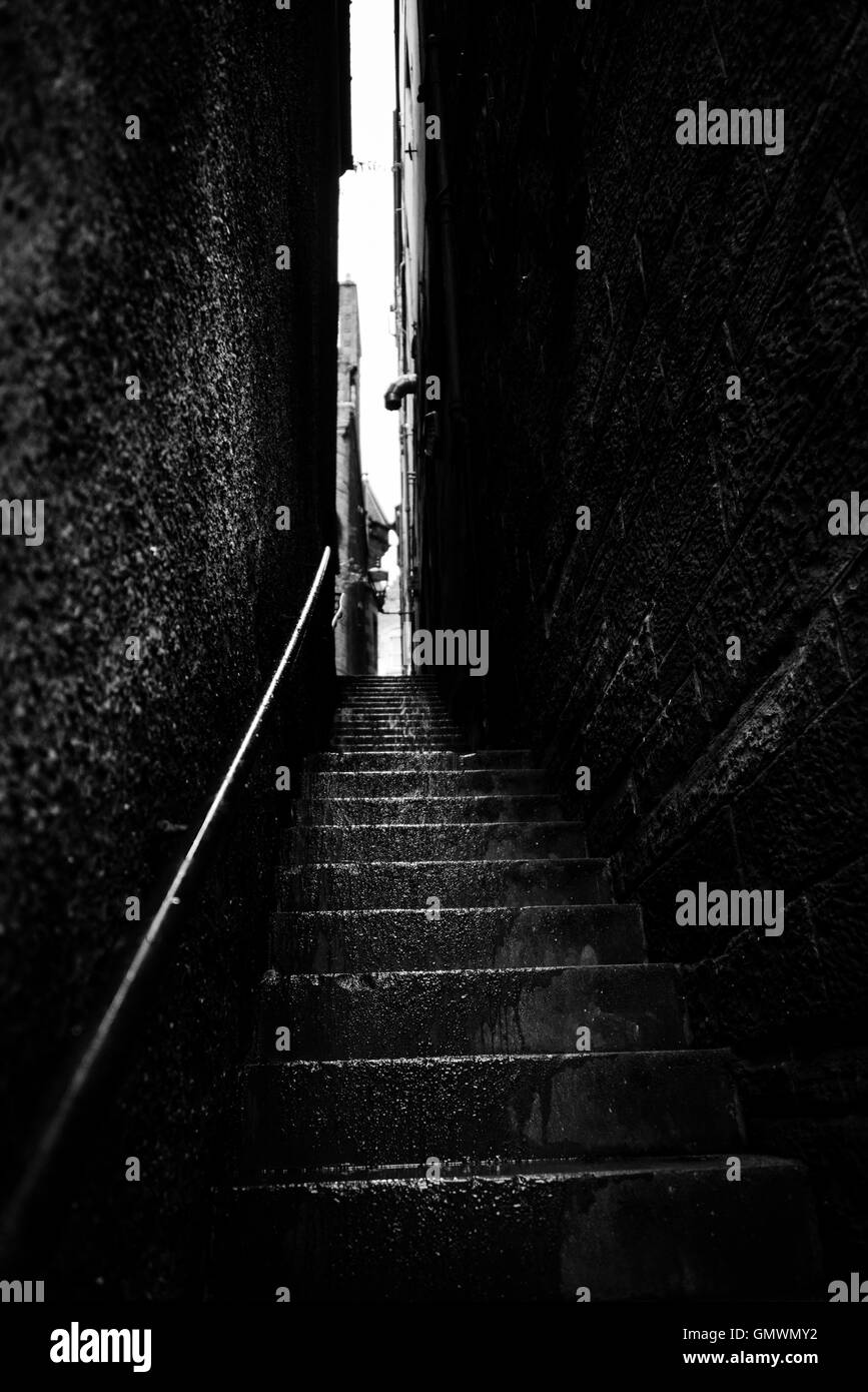 Schmale Treppe zwischen zwei hohen Mauern von einem regnerischen Tag, schwarz und weiß. In Edinburgh, Schottland, Großbritannien. Stockfoto