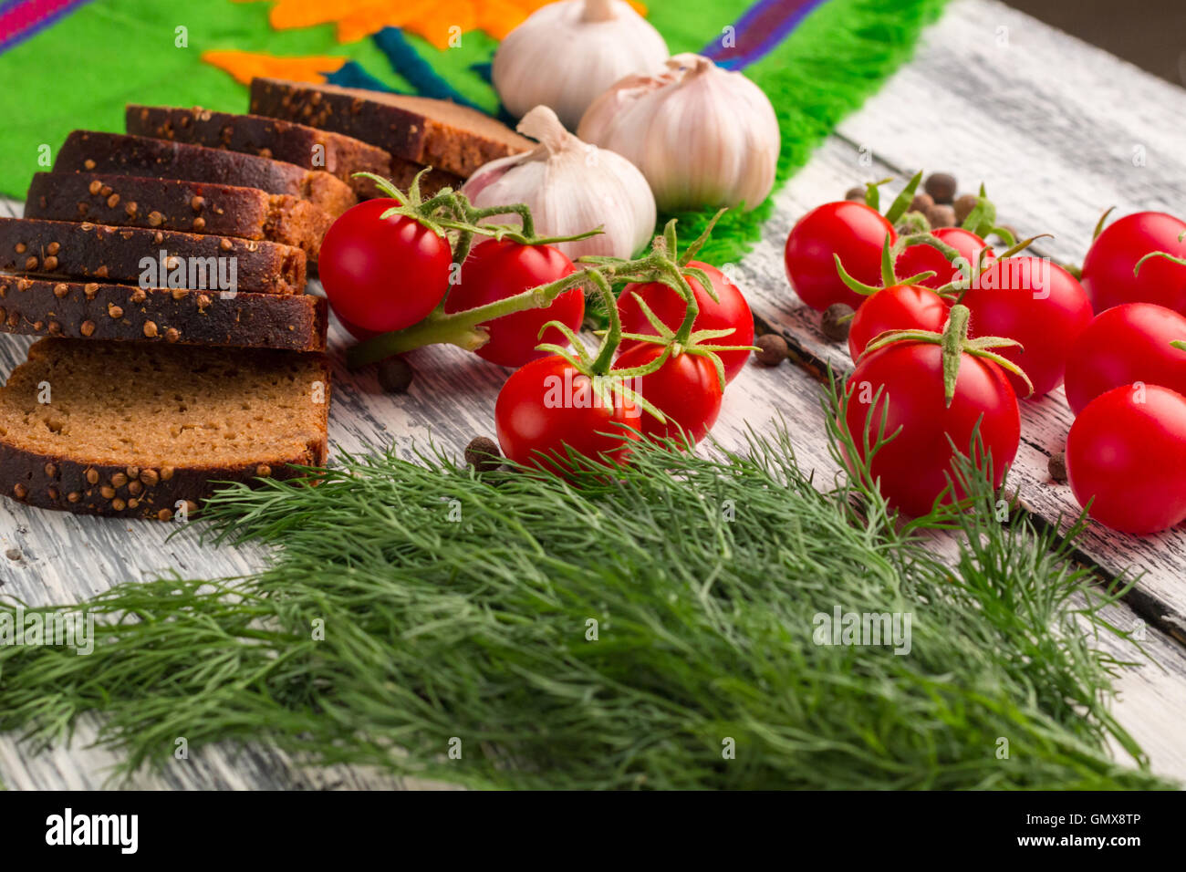 Stilleben auf hölzernen Hintergrund: Schwarzbrot, Knoblauch, Fenchel, Tomaten, Bayberry Pfeffer Stockfoto