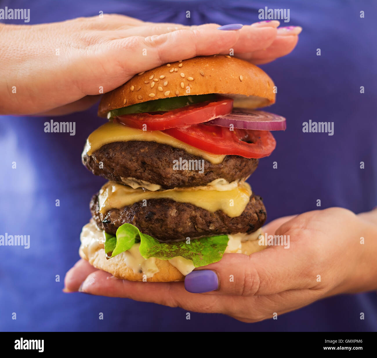 Big Sandwich - Hamburger Burger mit Rindfleisch, Käse, Tomaten und Tartar sauce in weiblichen Händen Stockfoto