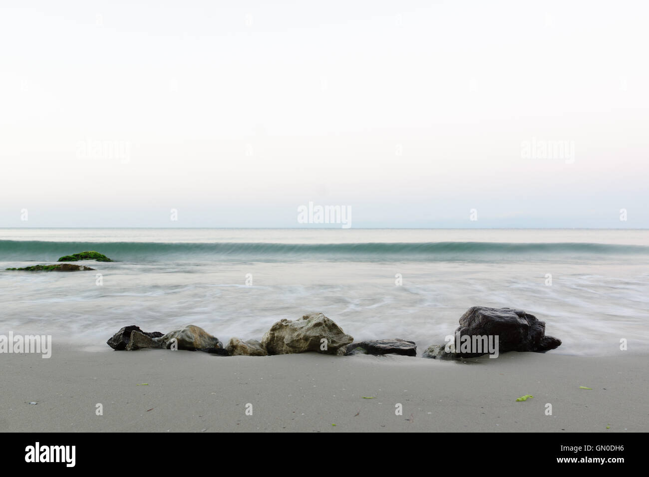 Steinen am Strand unter die ankommende Welle Stockfoto