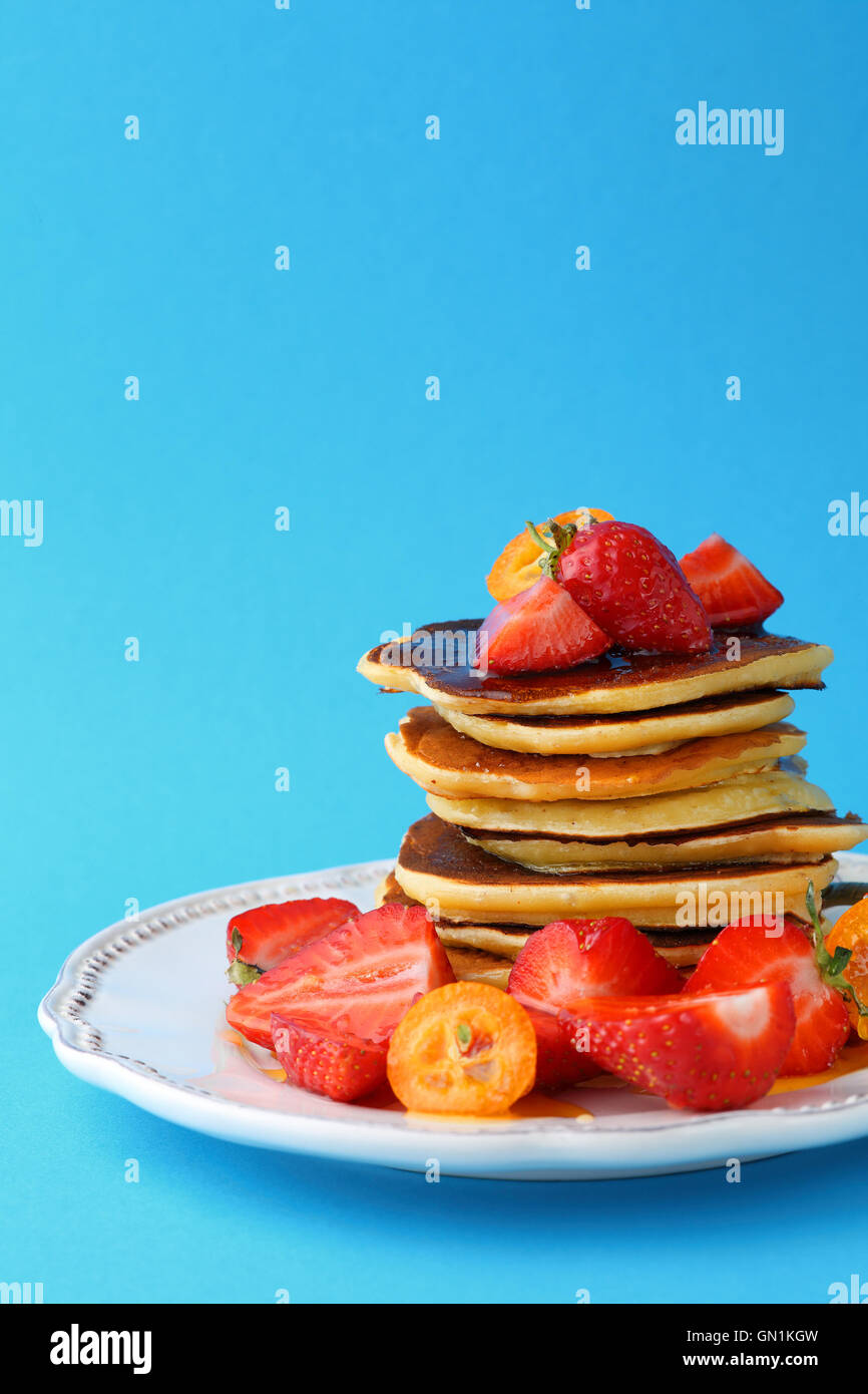 Warme Pfannkuchen mit frischen Früchten vor blauem Hintergrund Essen Nahaufnahme Stockfoto