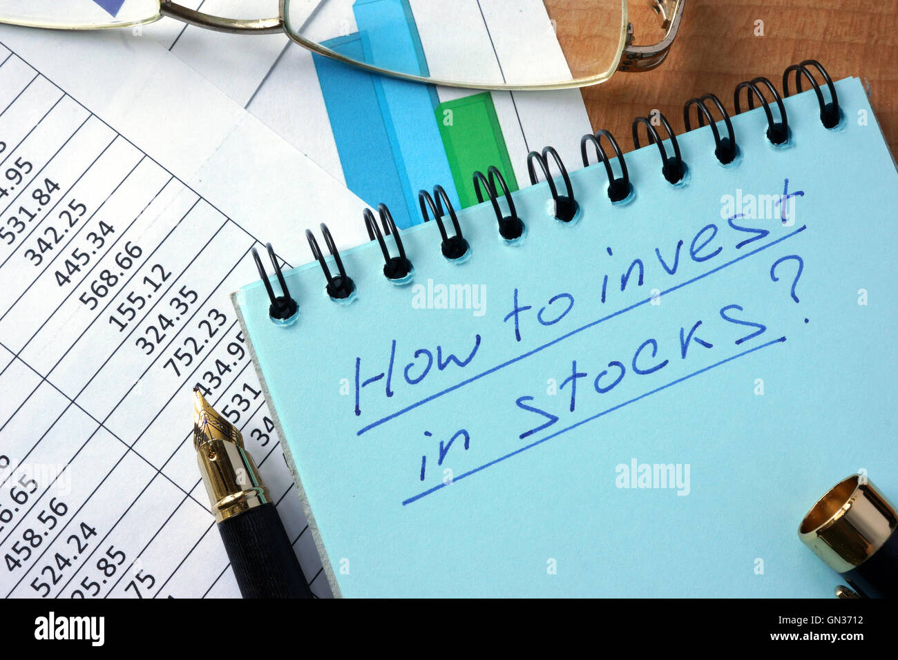 Notizblock mit Inschrift wie investieren in Aktien auf einem Tisch. Stockfoto