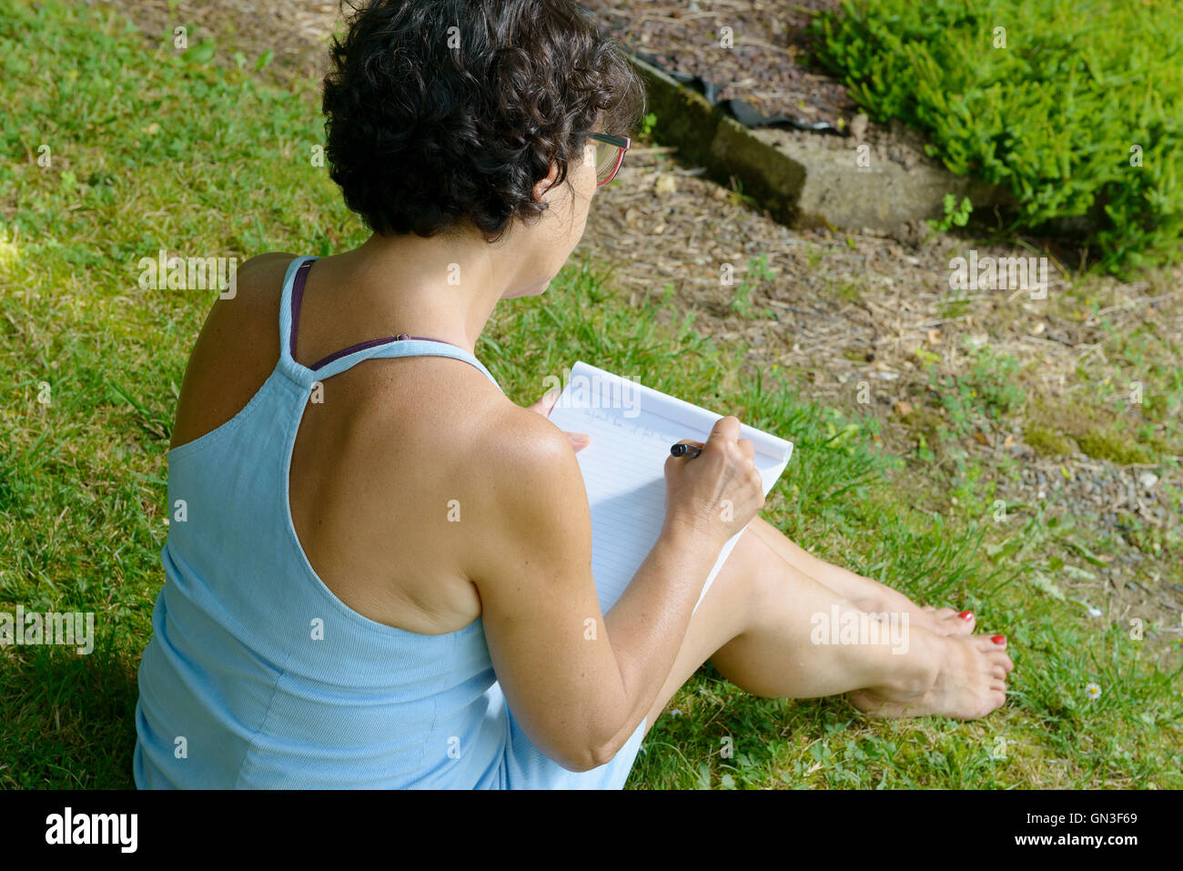 schöne Reife Frau schreibt einen Brief im Garten Stockfoto