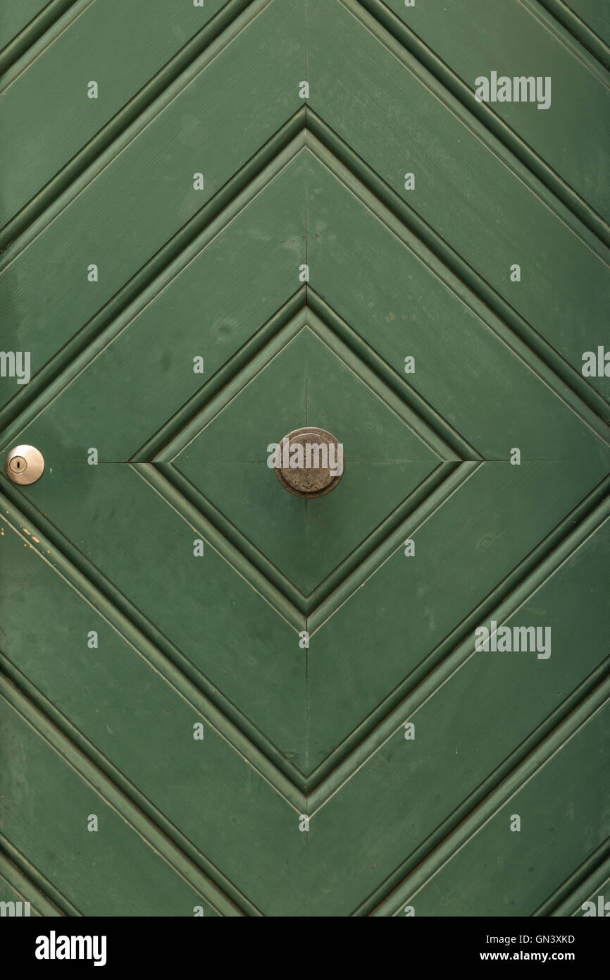 Ein grün bemalte Holztür mit Rautenmuster und runder Türknauf. Stockfoto