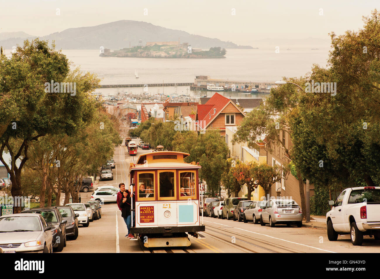 Eine Seilbahn kriecht oben Hyde Street, einer der San Francisco viele steile Straßen mit Alcatraz Island im Hintergrund. San Fra Stockfoto