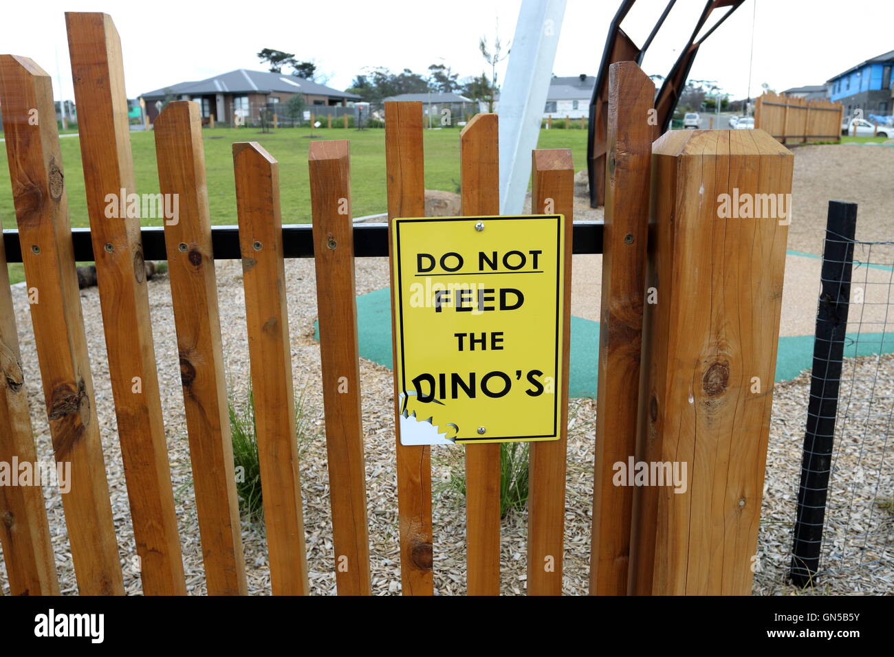 Der Dino gelbes Schild gegen Holzzaun tun nicht füttern Stockfoto