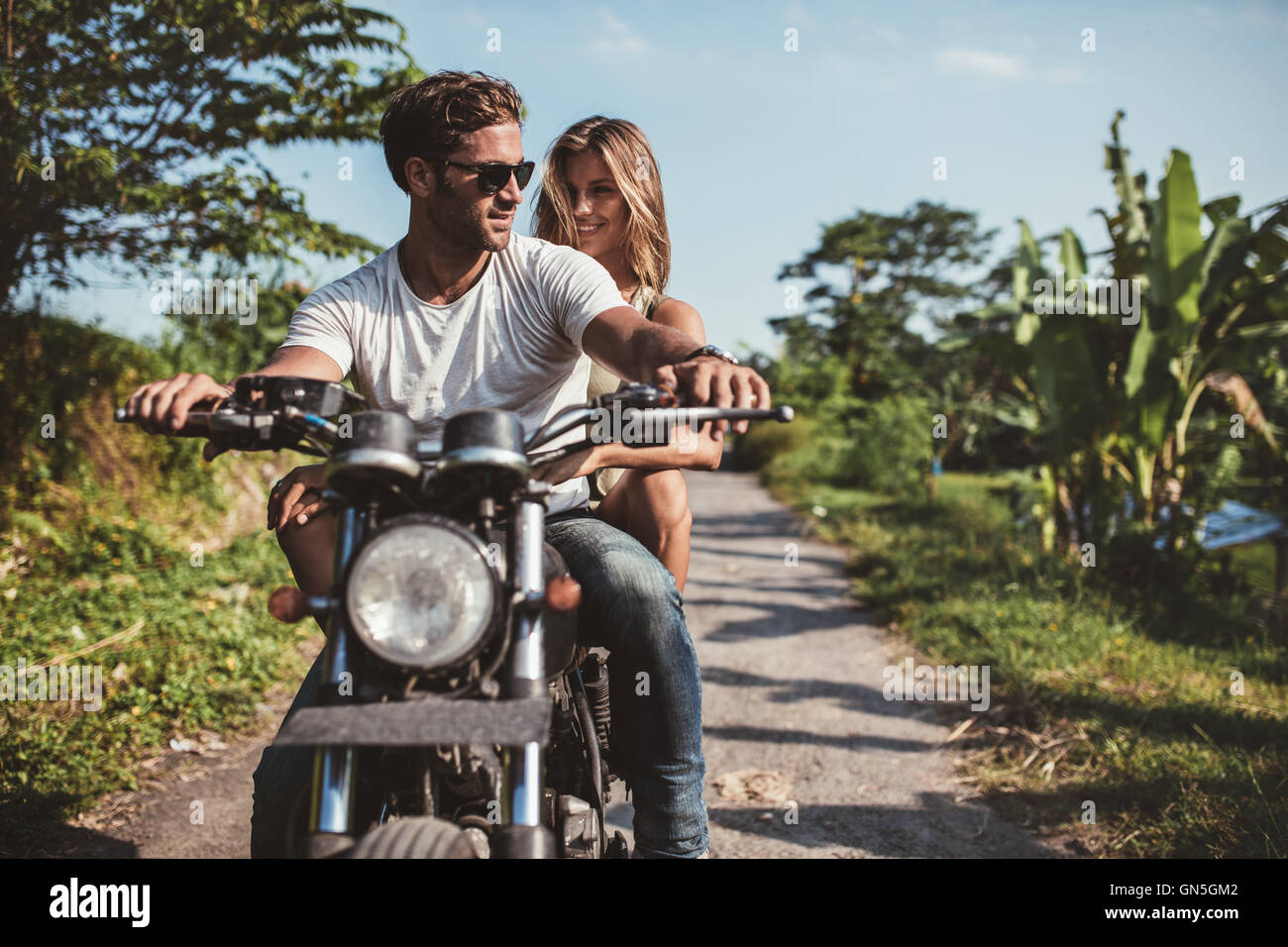 Aufnahme des jungen Paares auf dem Motorrad. Mann reitet auf einem Motorrad mit Freundin auf Landstraße. Stockfoto