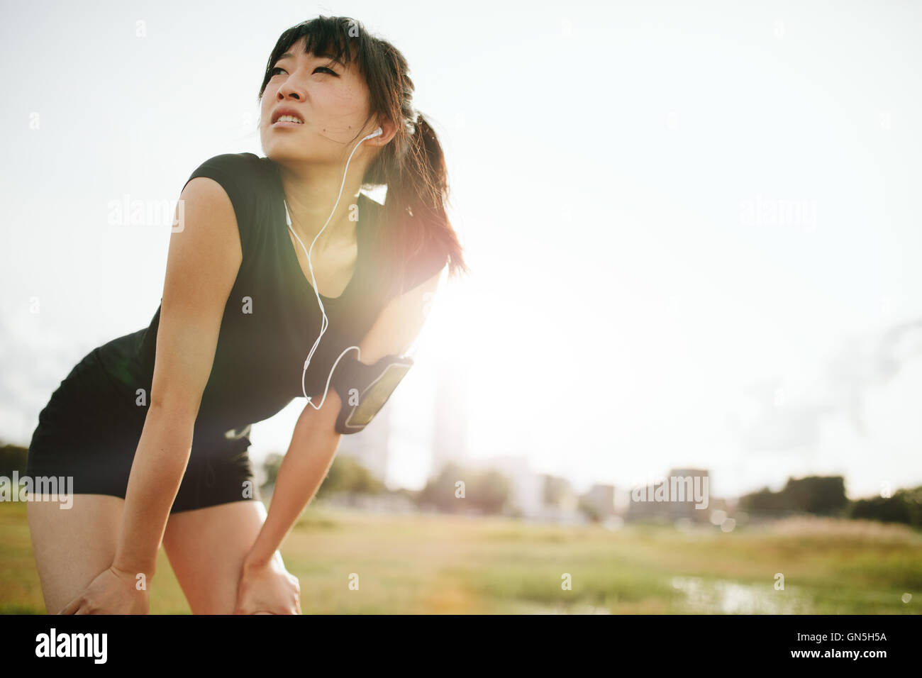 Junge chinesische Frau beugte sich über Sportausrüstung. Entschlossene Sport Frau sucht nach vorne laufen. Stockfoto