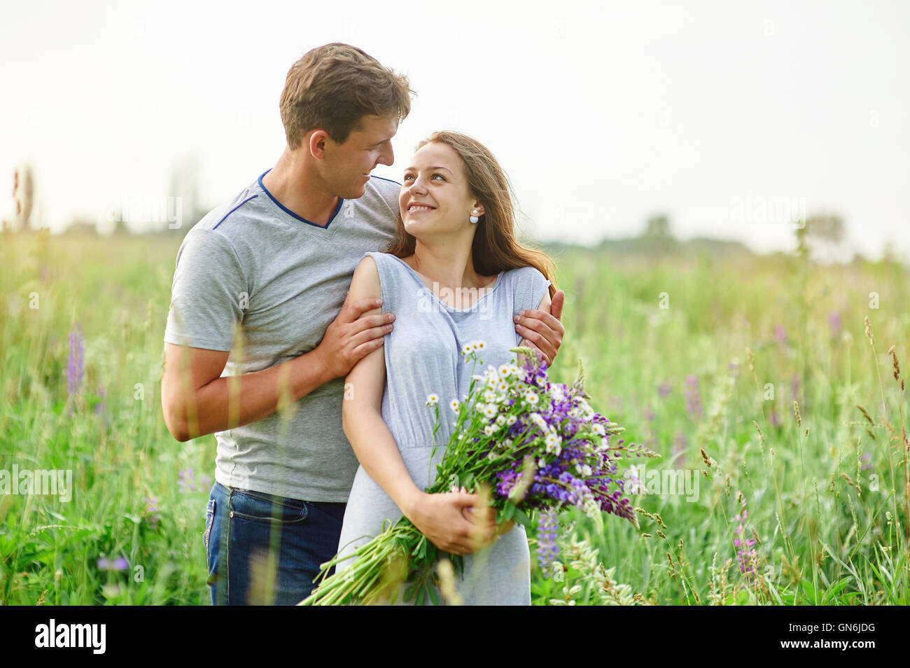 junges Paar in Liebe zu Fuß auf der Sommerwiese Stockfoto