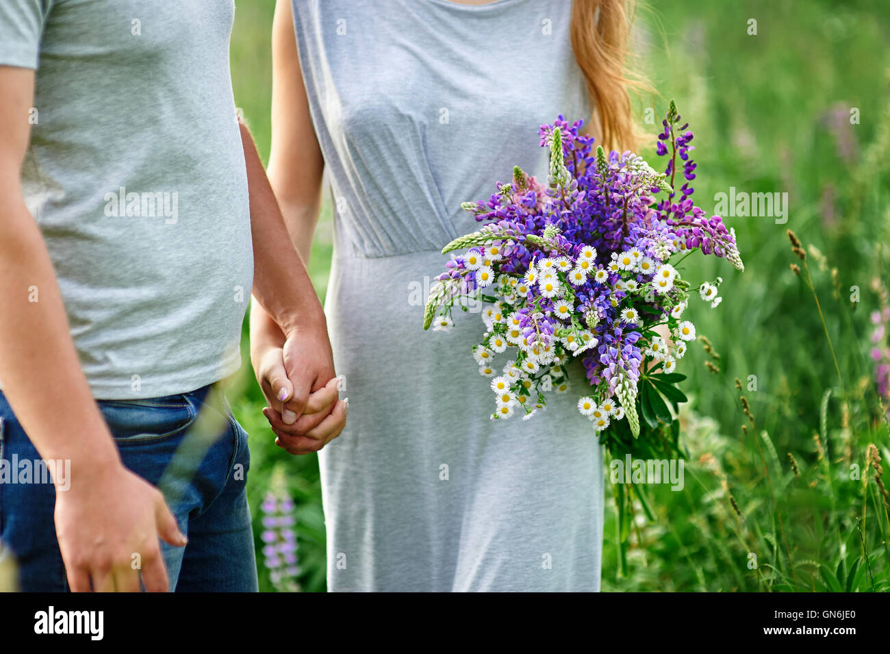 junges Paar in Liebe zu Fuß auf der Sommerwiese Stockfoto
