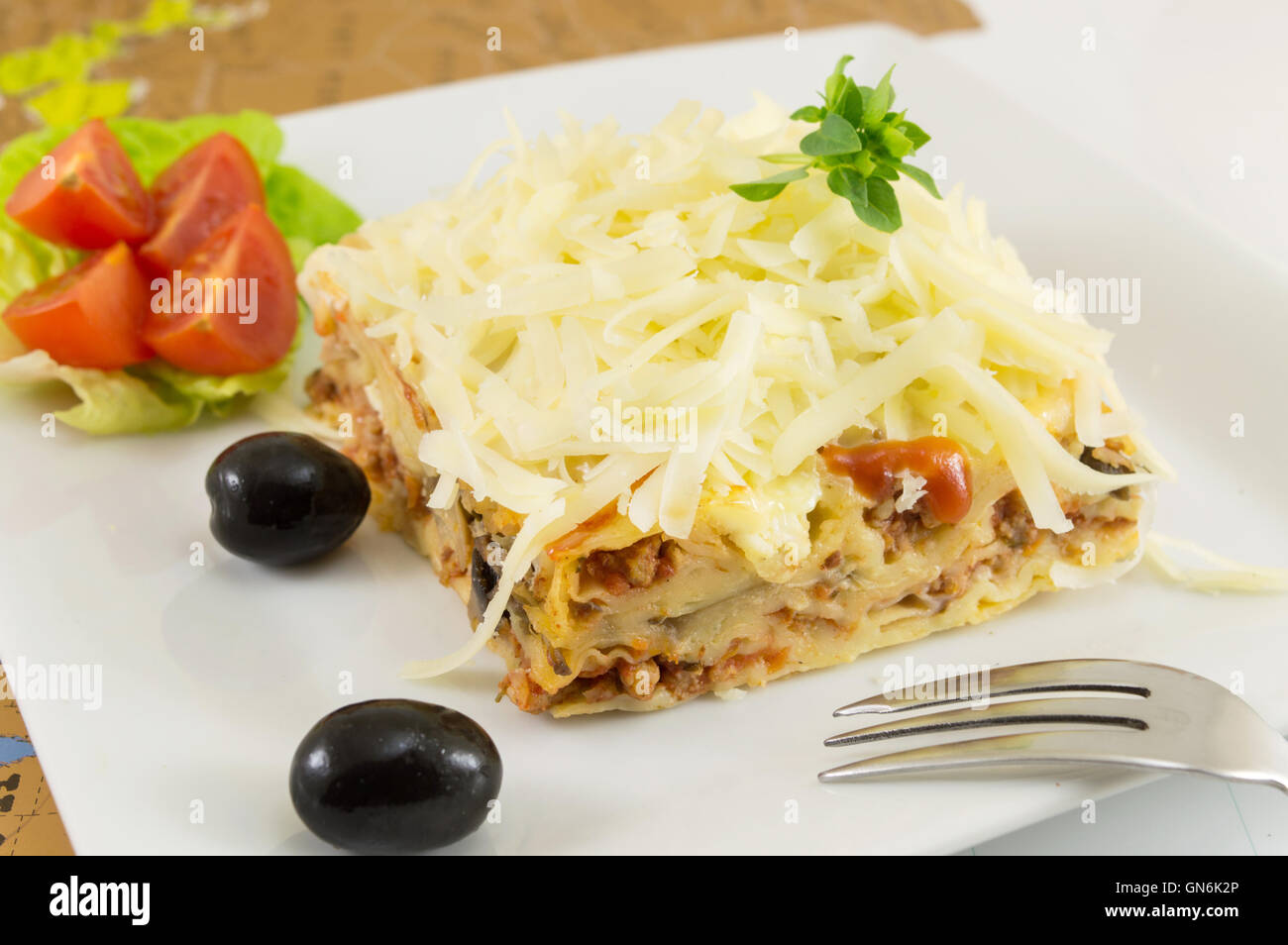 Lasagne-Teil mit frischem Gemüse auf einem Teller Stockfoto