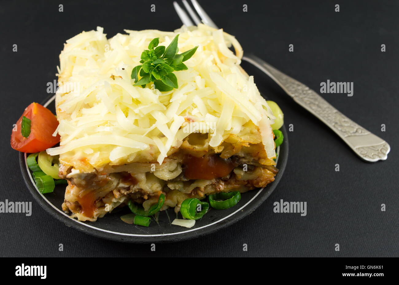 Portion Lasagne mit Gemüse auf einem dunklen Tisch Stockfoto
