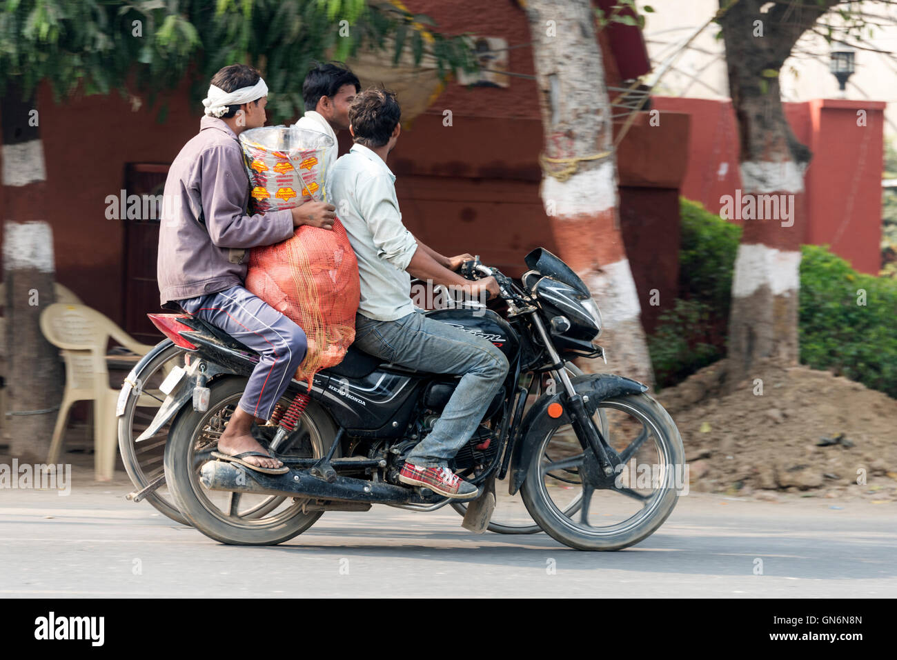 Zwei Fahrer mit einem großen Sack auf einem Motorrad auf der Hauptstraße in Agra, Uttar Pradesh, Indien, Stockfoto