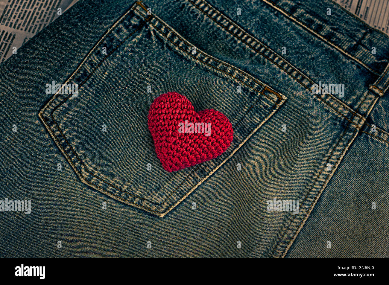 Kleine gestricktes rotes Herz auf Jeans-Tasche, Vintage-Stil, Ansicht von oben Stockfoto