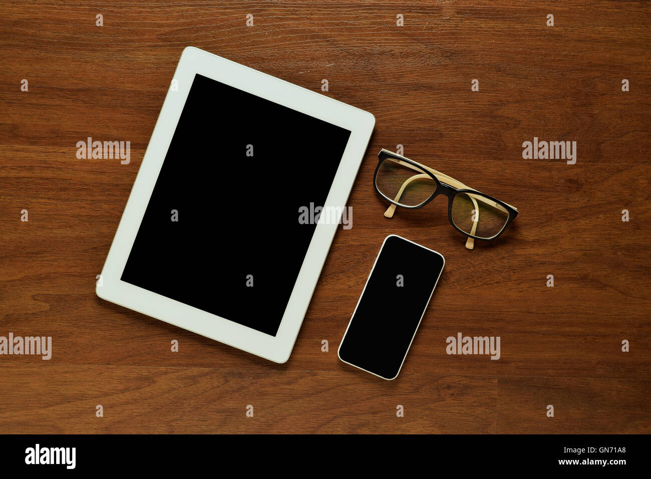 Draufsicht auf einen Tablet-PC, Smartphone und Gläser auf einem Schreibtisch aus Holz. Home Office Konzept. Business und Lifestyle. Exemplar. Stockfoto
