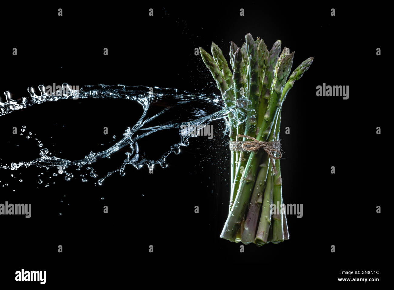 Spargel in Spritzer auf schwarzem Hintergrund. Close-up. Eine Reihe von Obst und Gemüse in Bewegung. Stockfoto