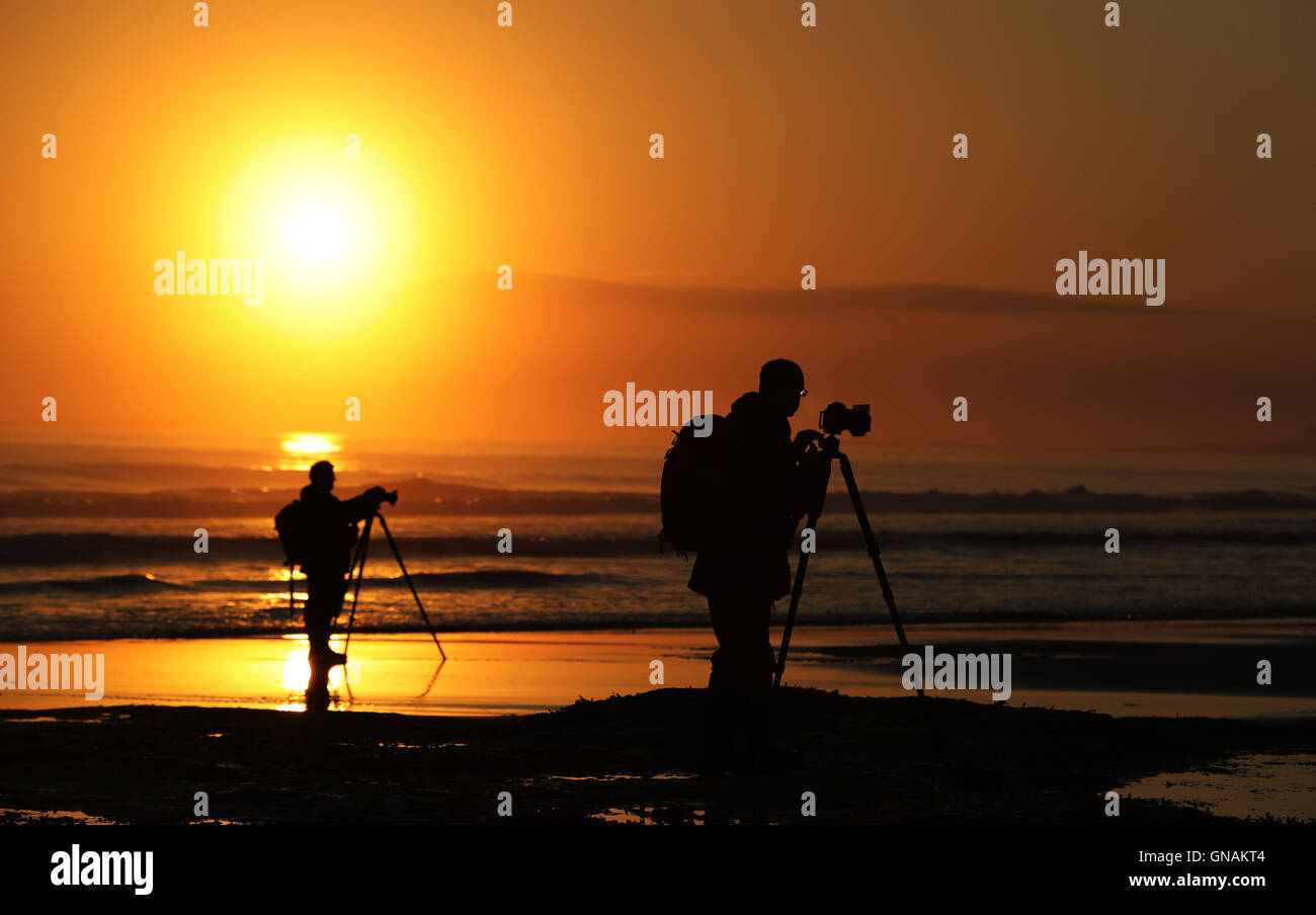 Fotografen zu erfassen, die Sonne über Bamburgh Strand in Northumberland, wie Briten Grill-Wetter für die Bank Holiday freuen können wie letzte Woche wenig wärmer weiter. Stockfoto