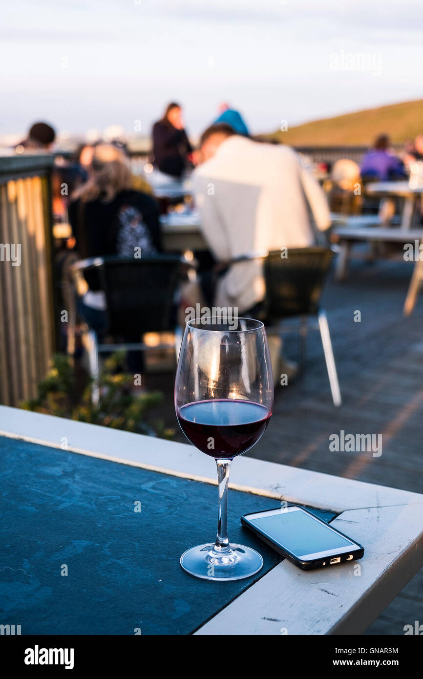Ein Glas Rotwein und einem Mobiltelefon auf einem Tisch. Stockfoto