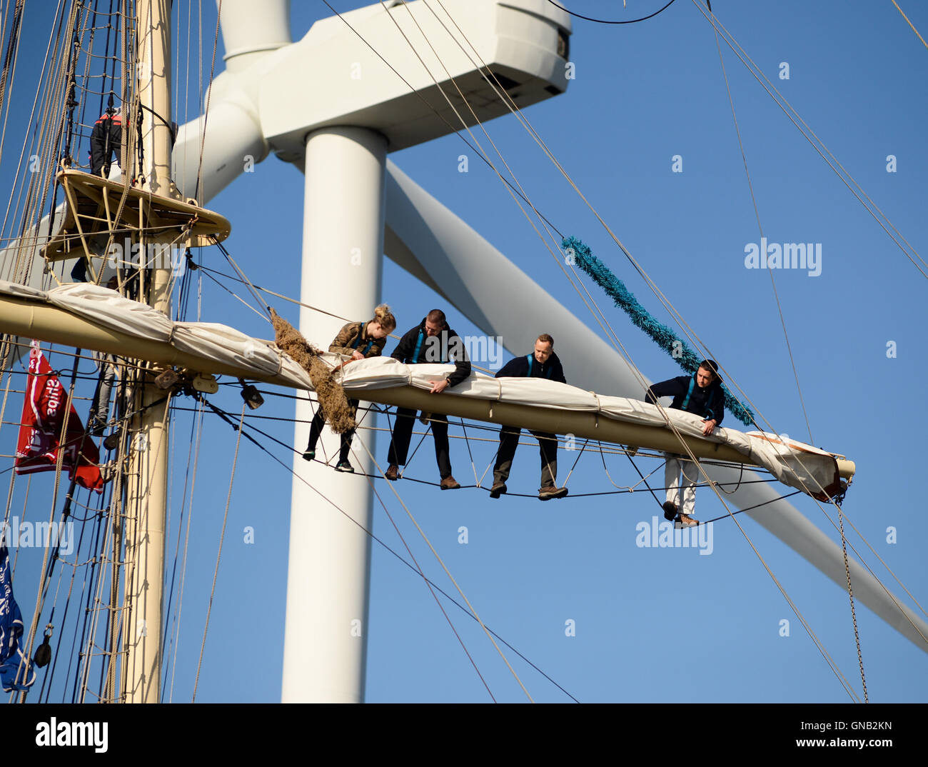 Blyth, Northumberland und Crew empor auf die polnische Brigg "Fryderyk Chopin" gegen ein 128 Meter hohen Windkraftanlage arbeiten. Stockfoto
