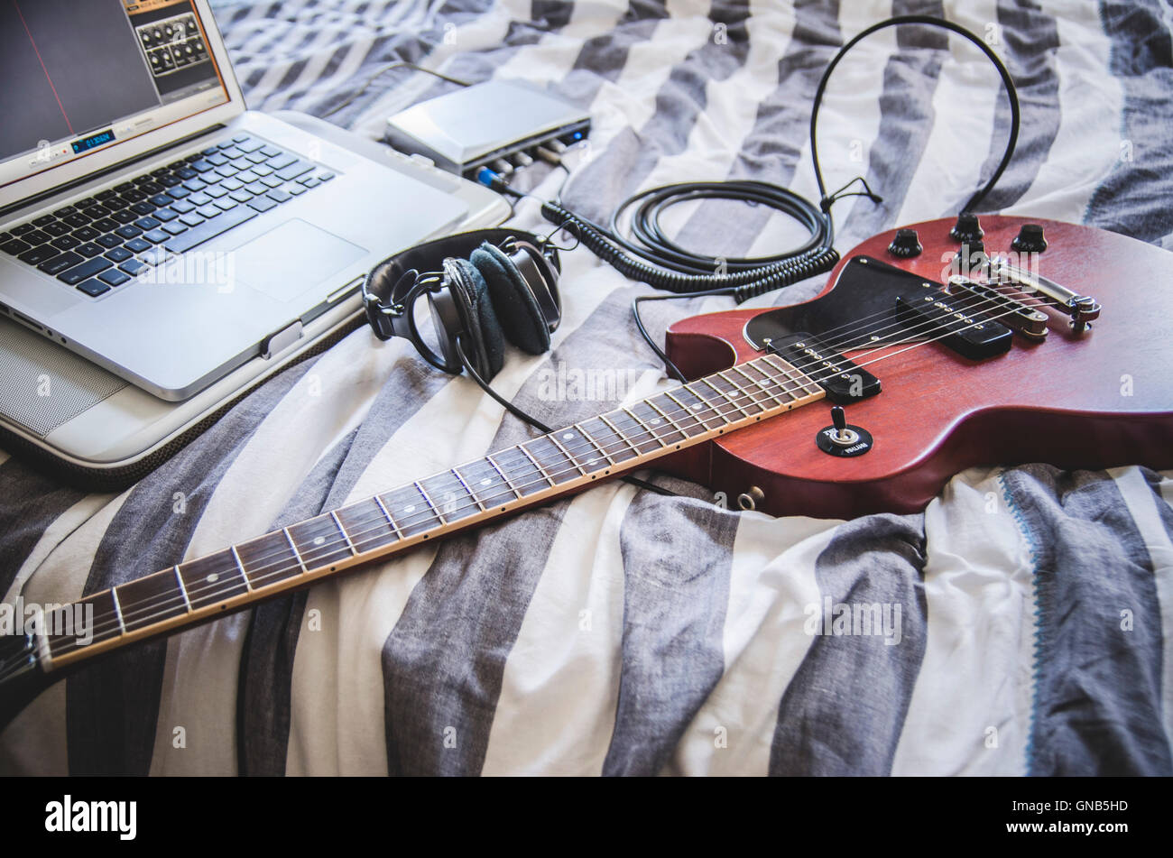 E-Gitarre und Kopfhörer eingesteckt in Home-Recording-Equipment und Laptop Stockfoto