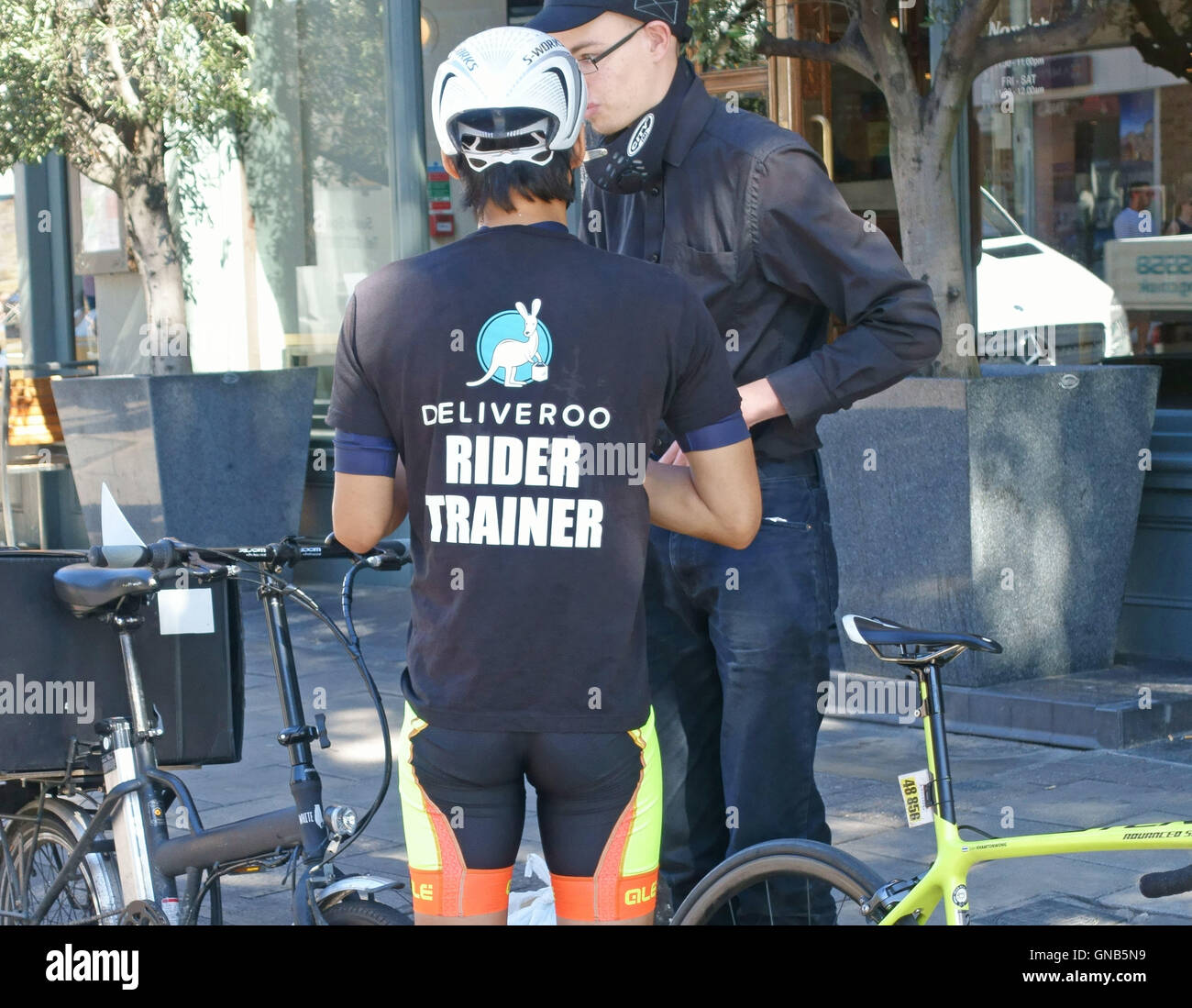 Deliveroo Reiter-Trainer mit Auszubildenden in London Straße Stockfoto