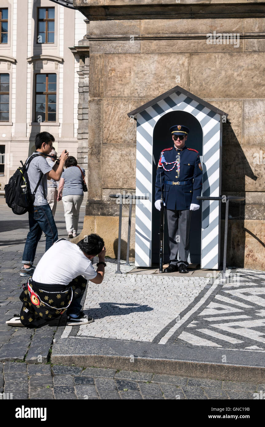 Ein paar asiatische Touristen fotografieren eine presidential Sentry auf Wache auf der Prager Burg in Prag, Tschechien. Stockfoto