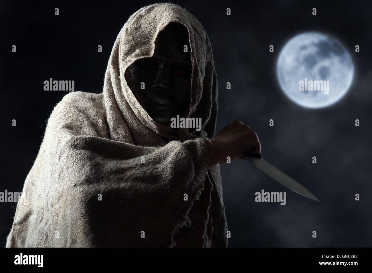 Der vermummte Mann mit einem großen Messer in Maske Stockfoto