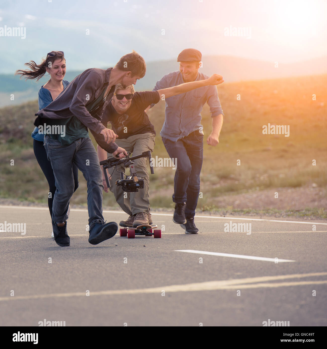 Gruppe von Freunden laufen, lachen und schießen mit der Kamera auf die  elektronischen Federung, der Kerl das longboard Stockfotografie - Alamy