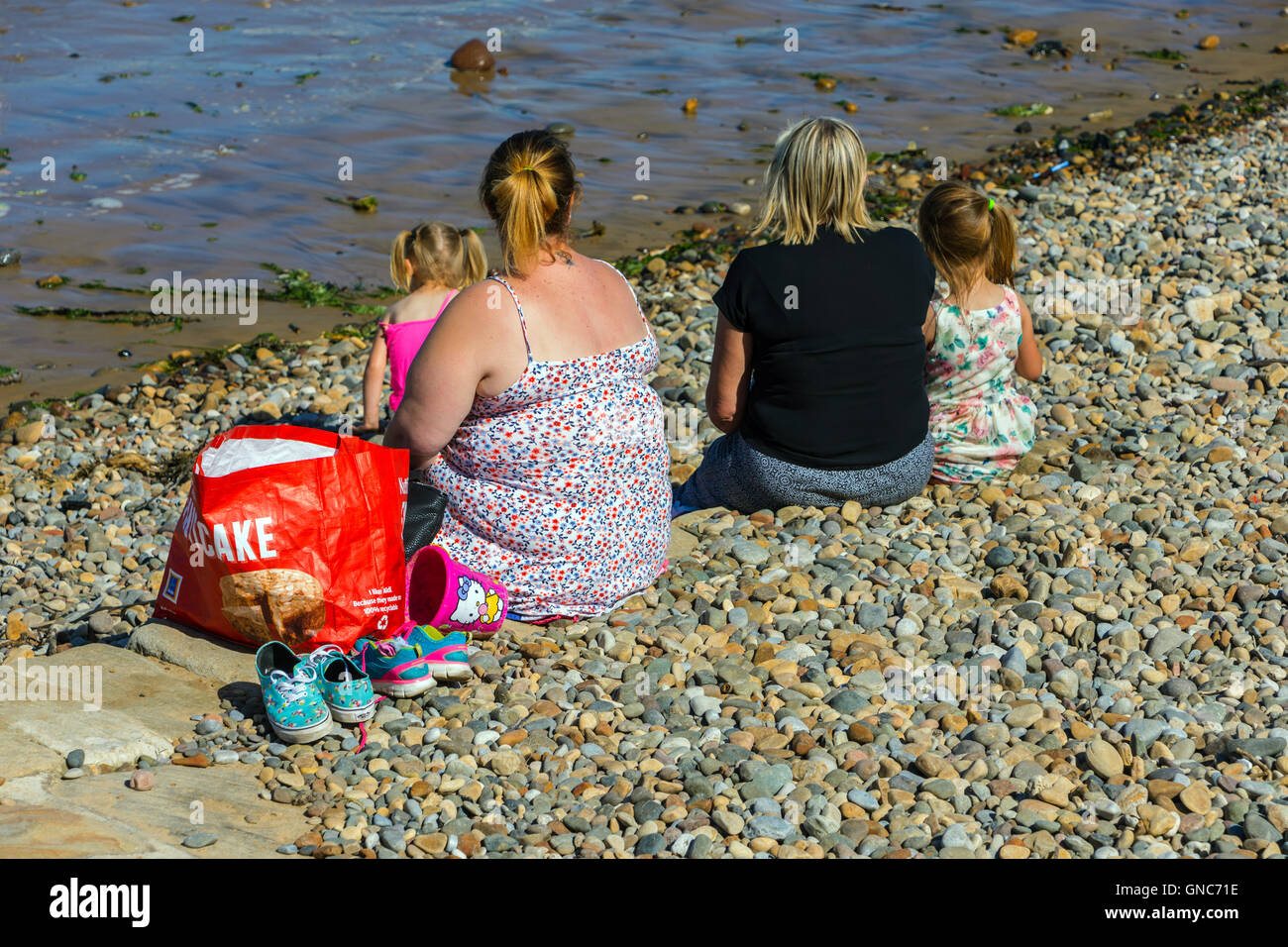 Zwei dicke Frauen mit Kindern am Strand, Saltburn am Meer, Yorkshire Stockfoto