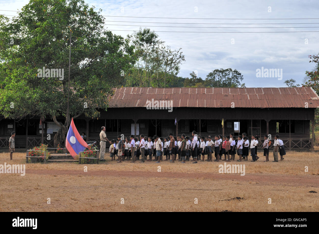 Süden von Laos, Schulkinder paradieren mit Lao Flagge Stockfoto