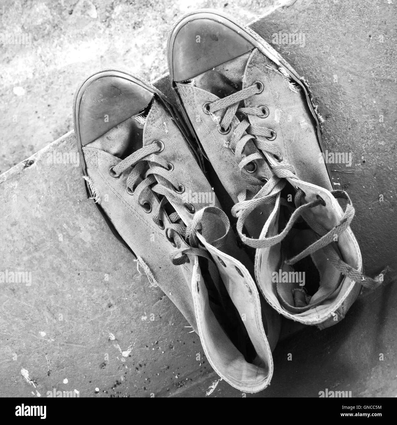 Paar alte Turnschuhe auf Betontreppen, Ansicht von oben stehen. Schwarz / weiß Retro-stilisierte Foto Stockfoto