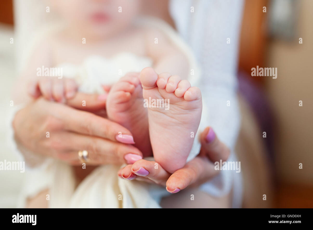 Mutter hält kleine Babys Füße auf Bett Stockfoto