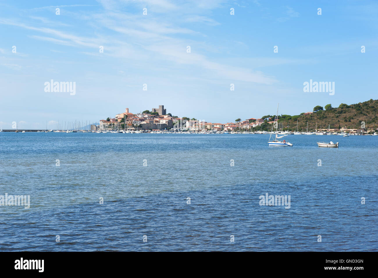 Talamone Village, Toskana, Italien. Ansicht mit Segelboot und eine Menge von einem Meer, kleine Altstadt mit Hafen im Hintergrund Stockfoto