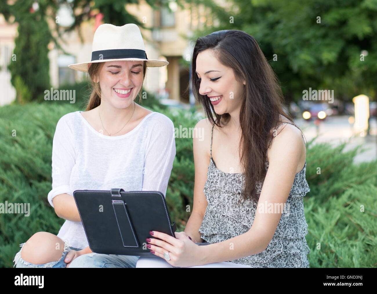 Zwei Freunde betrachten die Tablet-Gerät außerhalb Stockfoto