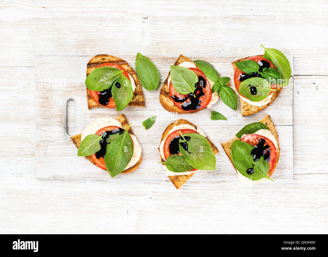 Caprese-Sandwiches mit Tomaten, Mozzarella, Basilikum und Balsamico-Glasur auf weißem lackiertem Holz Hintergrund Stockfoto