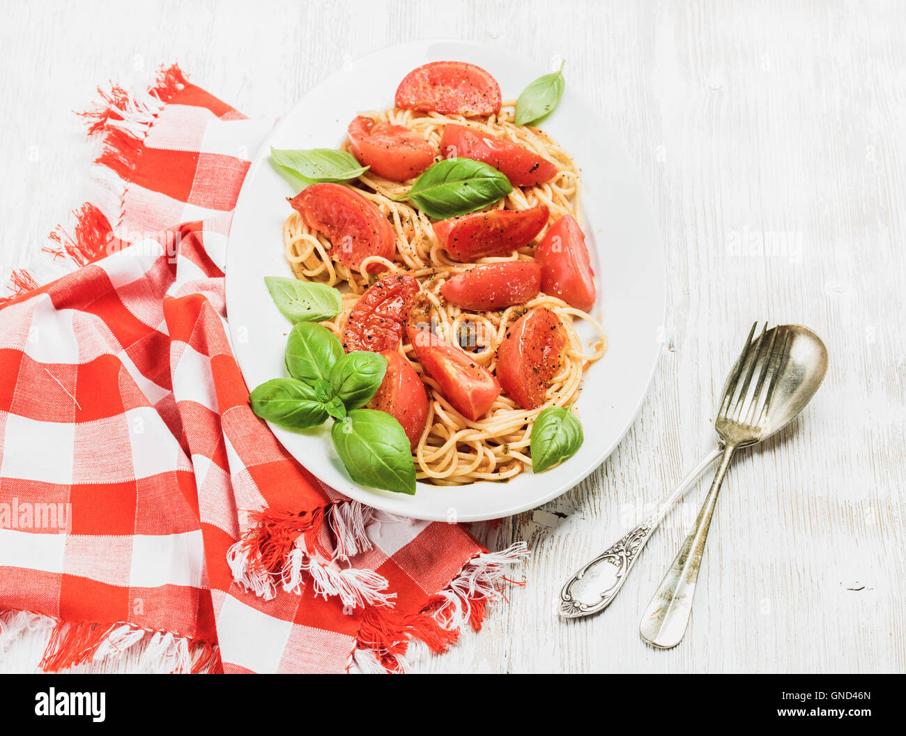 Spaghetti mit gebratenen Tomaten und frischem Basilikum auf weißem Hintergrund Stockfoto