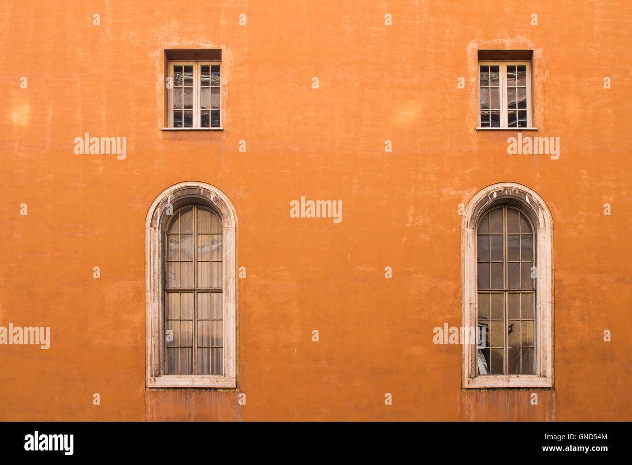 Typische orange Farbe der Fassade eines Hauses in Rom. Große dekorative Fenster und kleine traditionelle. Rom, Italien. Stockfoto