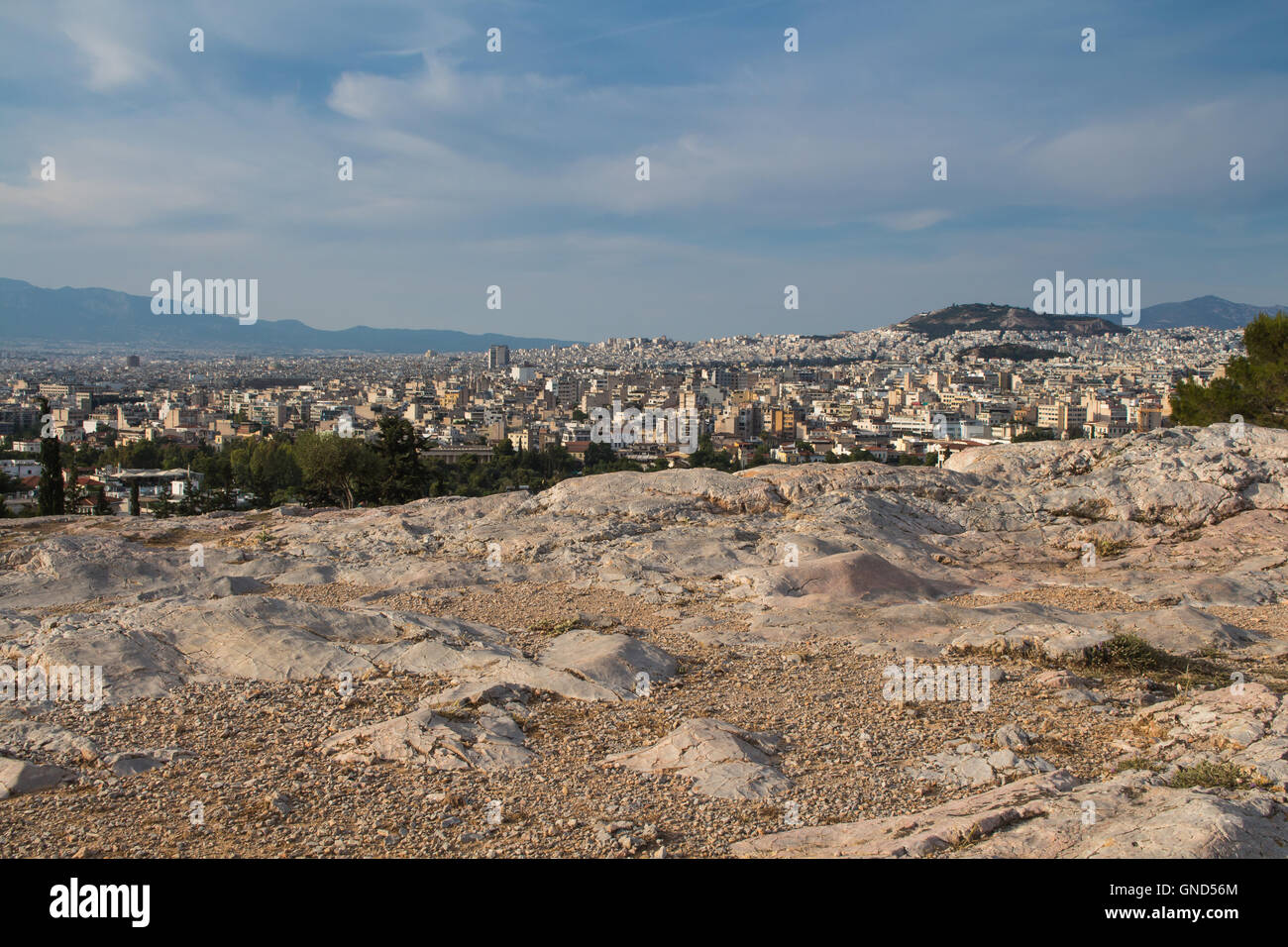 Blick vom Park auf einem Hügel an der griechischen Hauptstadt Athen. Häuser bis zu dem Hügel klettern. Berge im Hintergrund. Trübe frühen ev Stockfoto
