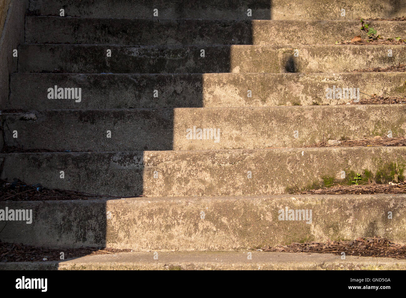 Alte Treppen in einem verlassenen Haus, diagonal aufgeteilt in einen hellen und schattigen Teil. Stockfoto