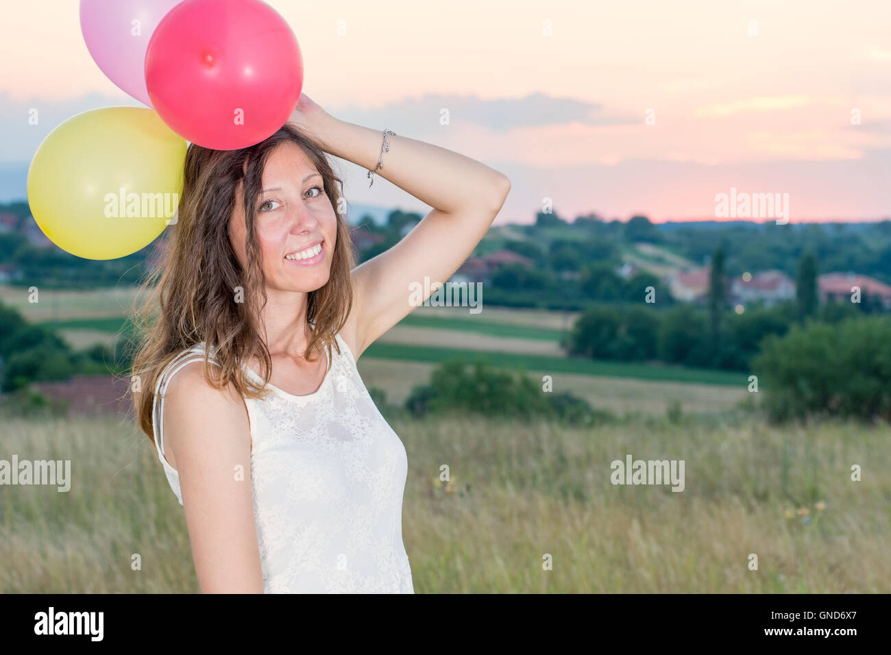 Junge Frau mit Ballons zum romantischen Sonnenuntergang Stockfoto