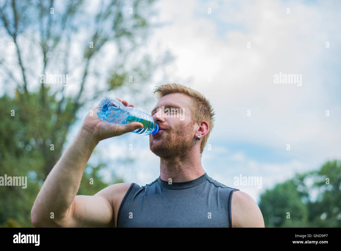 Athletische Sportart Man Trinkwasser aus der Flasche Stockfoto