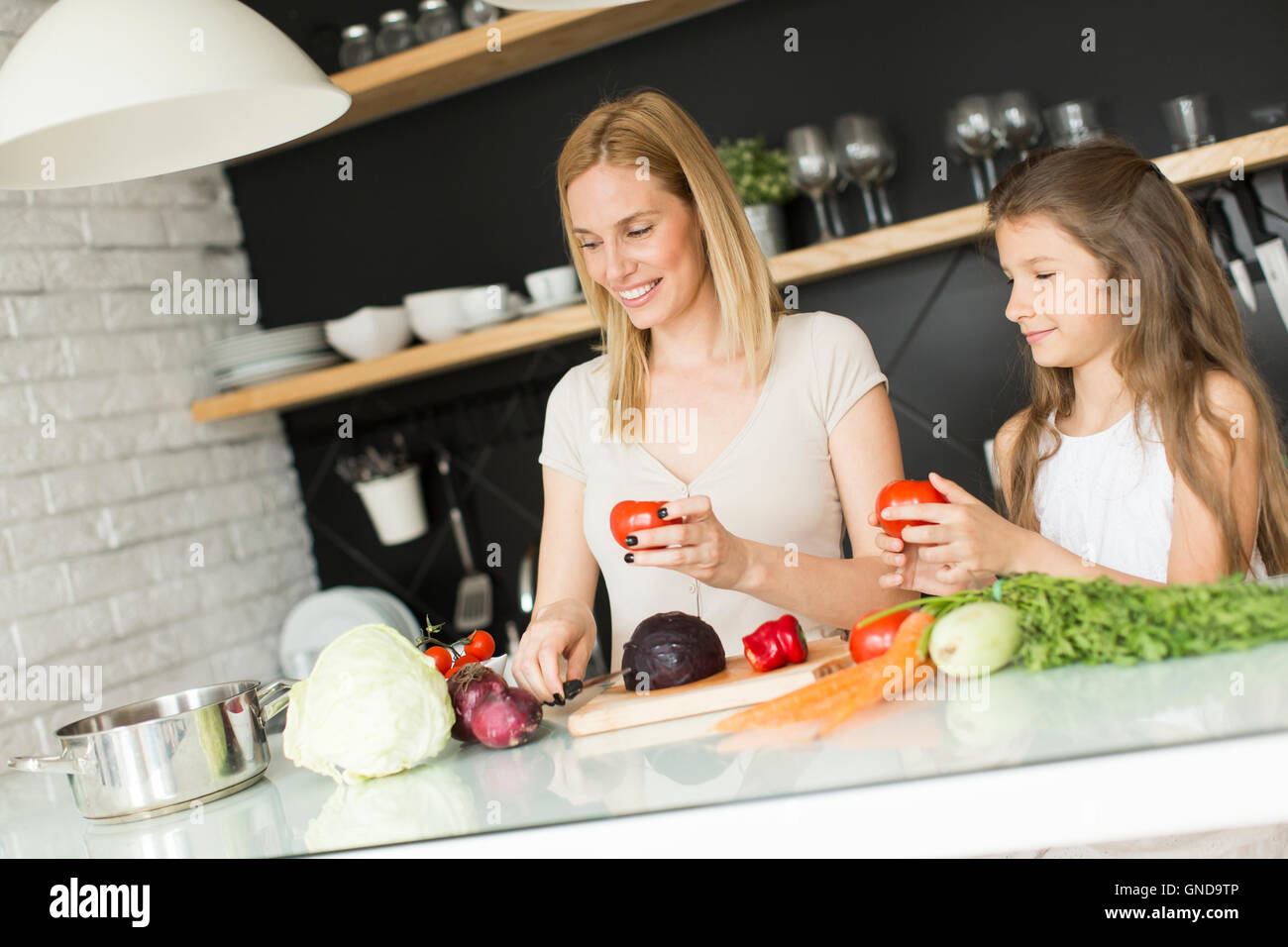 Mutter und Tochter vorbereiten und blending Smoothie aus frischen Früchten in der modernen Küche Stockfoto