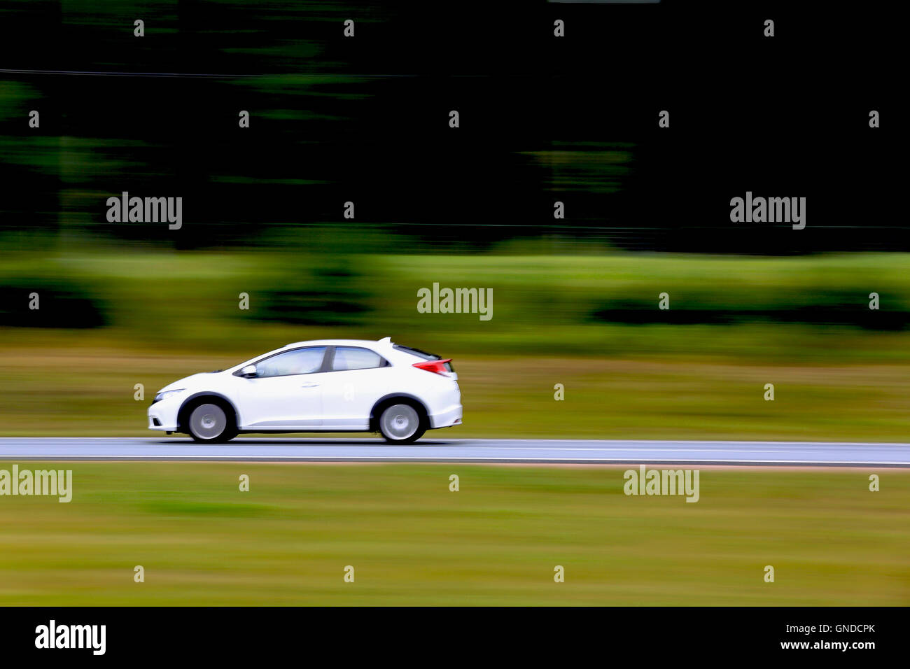 Kleines weißes Auto mit hoher Geschwindigkeit auf der Autobahn, Technik, Textfreiraum rechts schwenken. Stockfoto