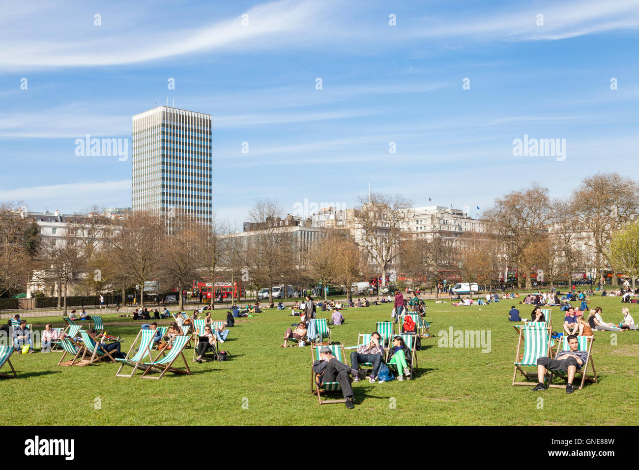 Menschen sitzen auf Liegestühlen im Hyde Park an einem sonnigen Tag im Frühling, London, England, Großbritannien Stockfoto